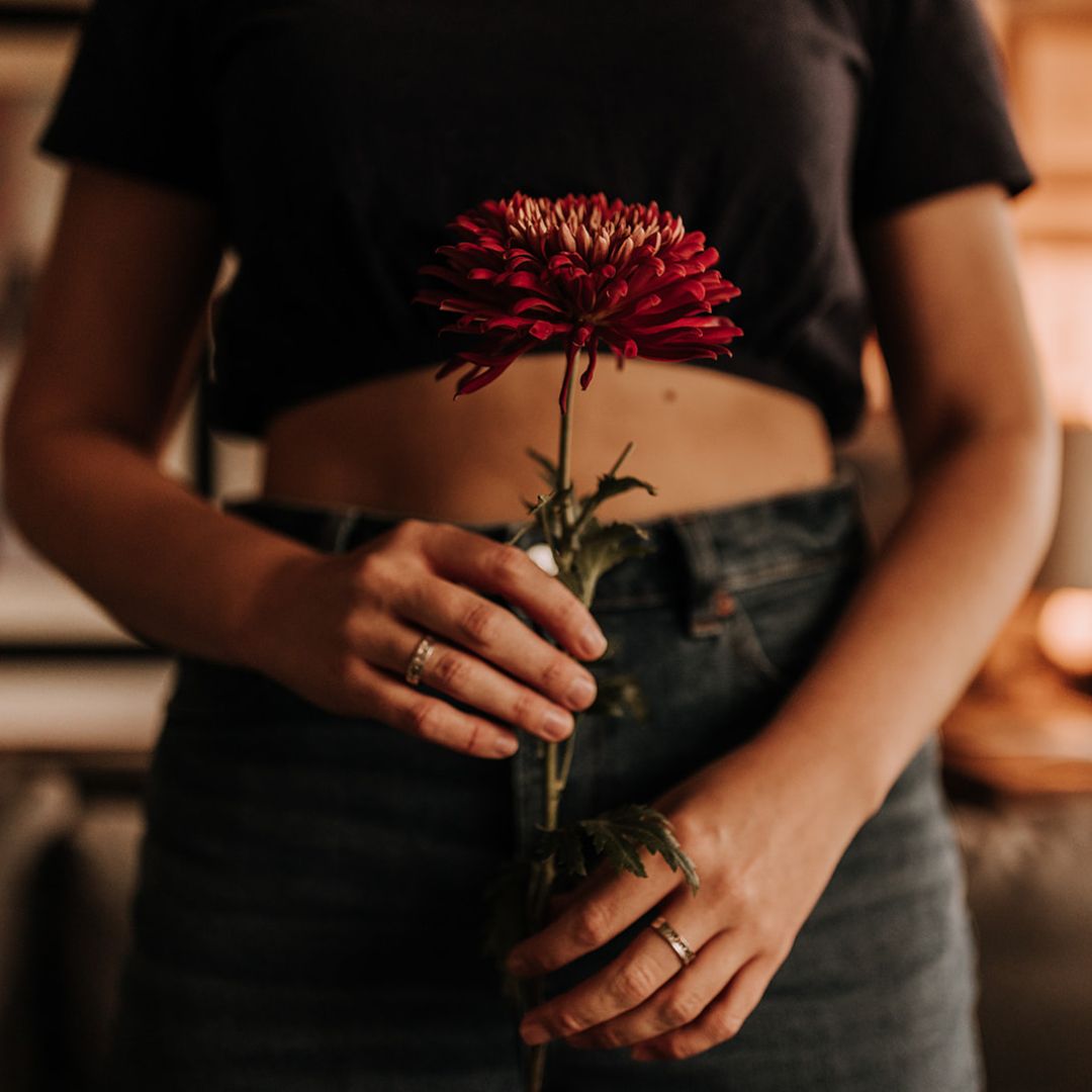 Lauren holds a red flower in front of her womb.
